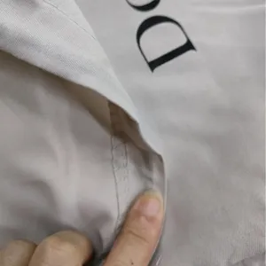 Close-up of beige polyester drawstring dust bag showing fabric texture and opening