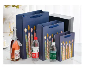 Size comparison of blue birthday gift bags with gold glitter candles and matching black box
