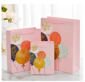 Close-up of pink birthday gift bags with glitter balloon patterns and ribbon handles