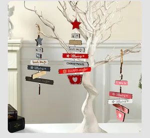 Detalle de adornos navideños de madera rústica colgados en un árbol blanco decorado.