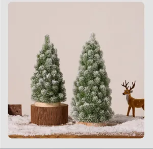 Detail of two mini frosted Christmas trees on a snowy wooden surface with a deer figurine.