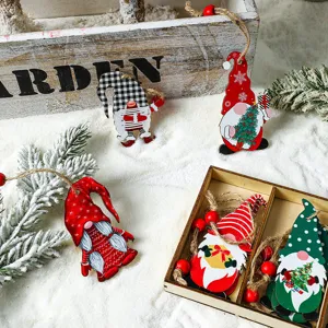 Set bunter, bemalter Weihnachtswichtel aus Holz auf Kunstschnee mit Tannennadeln.