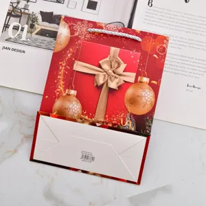 Festive red Christmas paper gift bag with handle featuring gift box and ornament print