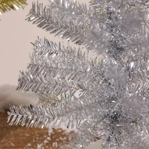 Nahaufnahme eines schimmernden silbernen Mini-Weihnachtsbaums mit glänzender Lametta-Textur.
