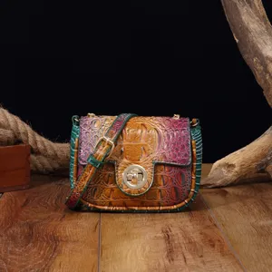 Vista detallada de un bolso bandolera vintage multicolor con patrón de cocodrilo y hebilla dorada.