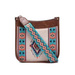 Detalle de un bolso bandolera bohemio con un estampado geométrico y correa marrón