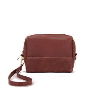 Primer plano de una bolsa de cuero marrón con clip de correa de muñeca dorado.