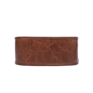 Primer plano de bolso bandolera vintage de cuero sintético marrón con textura envejecida