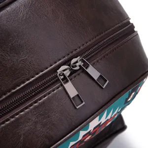 Close-up of durable metal double zipper and brown textured leather on Aztec backpack