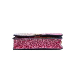 Vista detallada de un bolso bandolera rosa con relieve de cocodrilo y cierre de metal