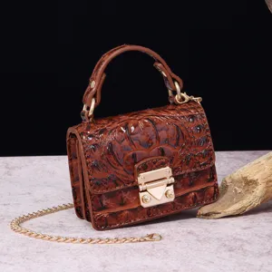 Detalle de mini bolso vintage marrón con relieve de cocodrilo y cierre metálico dorado.