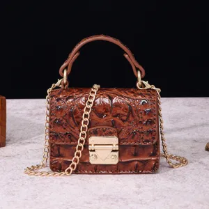 Detalle del bolso vintage marrón con estampado de cocodrilo y cierre metal dorado.