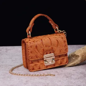 Vista detallata del bolso bandolera vintage naranja con diseño de cocodrilo y cadena oro