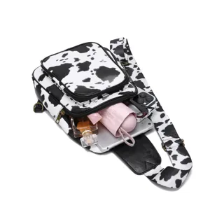 Detailed view of cow print sling bag showing capacity for tablet, umbrella and phone
