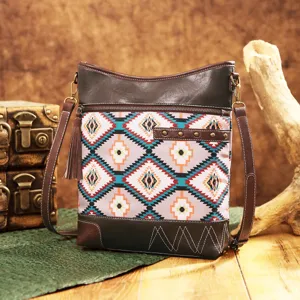 Vintage Aztec print crossbody bag with tassel and stud details on a rustic background