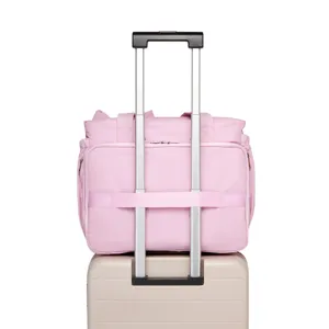 Dettaglio della borsa da viaggio rosa con fascia per trolley su manico della valigia