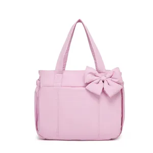 Primo piano di una borsa tote in nylon rosa con un fiocco decorativo molto elegante.