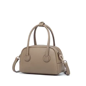 Vista lateral de un mini bolso Boston de cuero topo con detalles metálicos dorados