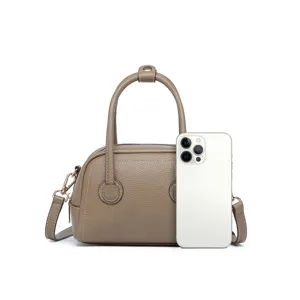 Mini bolso Boston de piel topo con un teléfono para comparar el tamaño