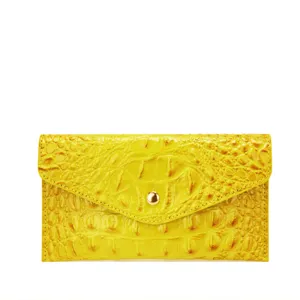 Primer plano de cartera de cuero amarillo con relieve de cocodrilo y botón dorado.