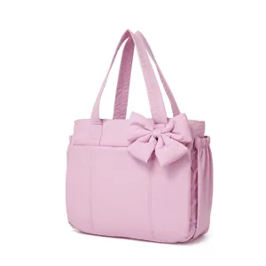 Dettaglio di una borsa tote in nylon rosa con un grande fiocco e tasche laterali.
