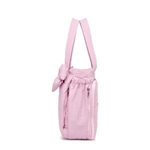 Vista laterale di una borsa a tracolla in nylon imbottita rosa con fiocco e cerniere.