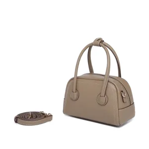 Vista lateral de un mini bolso Boston de cuero topo con correa de hombro extraíble.