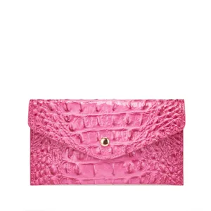 Vista de detalle de una cartera tipo sobre rosa con grabado de cocodrilo y broche.