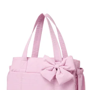 Vista dettagliata di una borsa tote rosa imbottita con un grande fiocco e manici robusti.