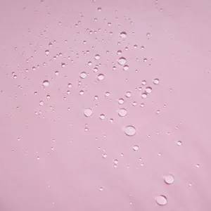 Primo piano del tessuto impermeabile rosa con gocce d'acqua che mostrano la trama.