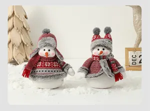 Gros plan de deux bonhommes de neige de Noël en peluche vêtus d'habits d'hiver rouges.