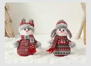 Détail de deux bonhommes de neige de Noël en peluche avec bonnets et écharpes rouges.