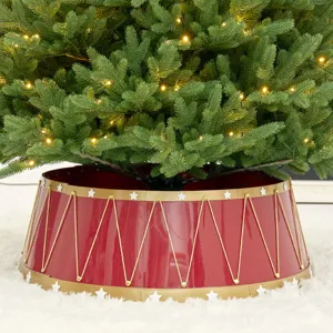 Festive red and gold drum style Christmas tree collar with star patterns on white rug