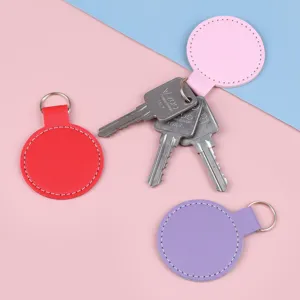 Lot de porte-clés ronds en cuir coloré avec anneaux métalliques et coutures.