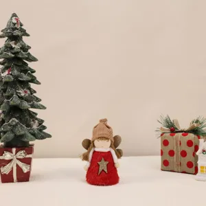 Close-up of a plush Christmas angel ornament with a red dress and gold star detail.