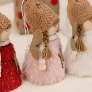 Close-up of plush Christmas angel ornaments with fuzzy dresses and knitted hats.