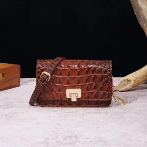 Detalle de un bolso bandolera vintage marrón con motivo de cocodrilo y cierre dorado.