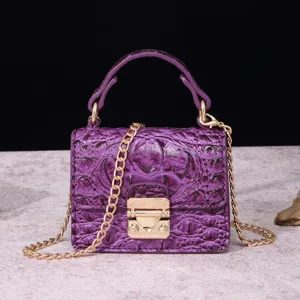 Primer plano de un mini bolso morado con efecto cocodrilo, cadena dorada y cierre retro