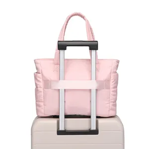 Detailed view of a pink quilted travel bag showing its functional back luggage sleeve