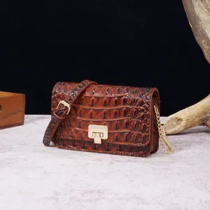 Detalle del bolso bandolera vintage marrón con grabado de cocodrilo y cierre dorado