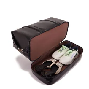 Detalle del bolso de viaje de cuero negro con compartimento inferior para zapatos