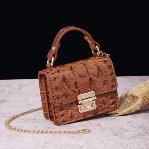 Vista detallada de un bolso vintage marrón con patrón de cocodrilo y cadena dorada.