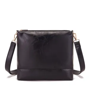 Vista detallada de un elegante bolso bandolera de cuero negro con herrajes dorados.