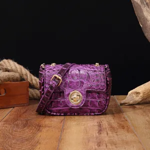Detalle de un bolso bandolera vintage morado con textura de cocodrilo y cierre de oro