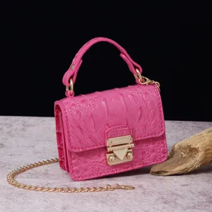 Vista macro detallada del mini bolso fucsia con relieve de cocodrilo y cierre oro.