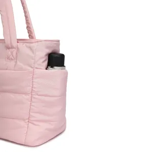 Close-up detail of the side pocket on a stylish pink quilted tote bag with an umbrella inside