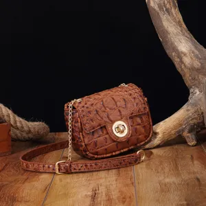 Detalle de bolso bandolera vintage marrón con relieve de cocodrilo y cadena dorada.