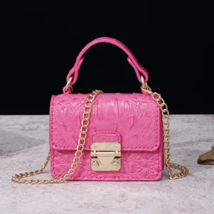 Primer plano de un mini bolso rosa grabado en cocodrilo con cadena de oro y cierre