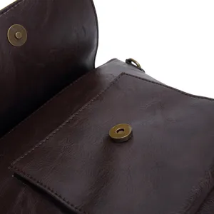 Detailed macro view of the magnetic snap closure on a dark brown vintage faux leather bag