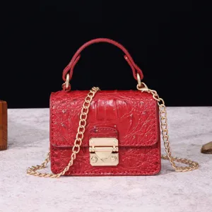 Primer plano detallado de minibolso rojo con efecto cocodrilo y elegante cierre dorado